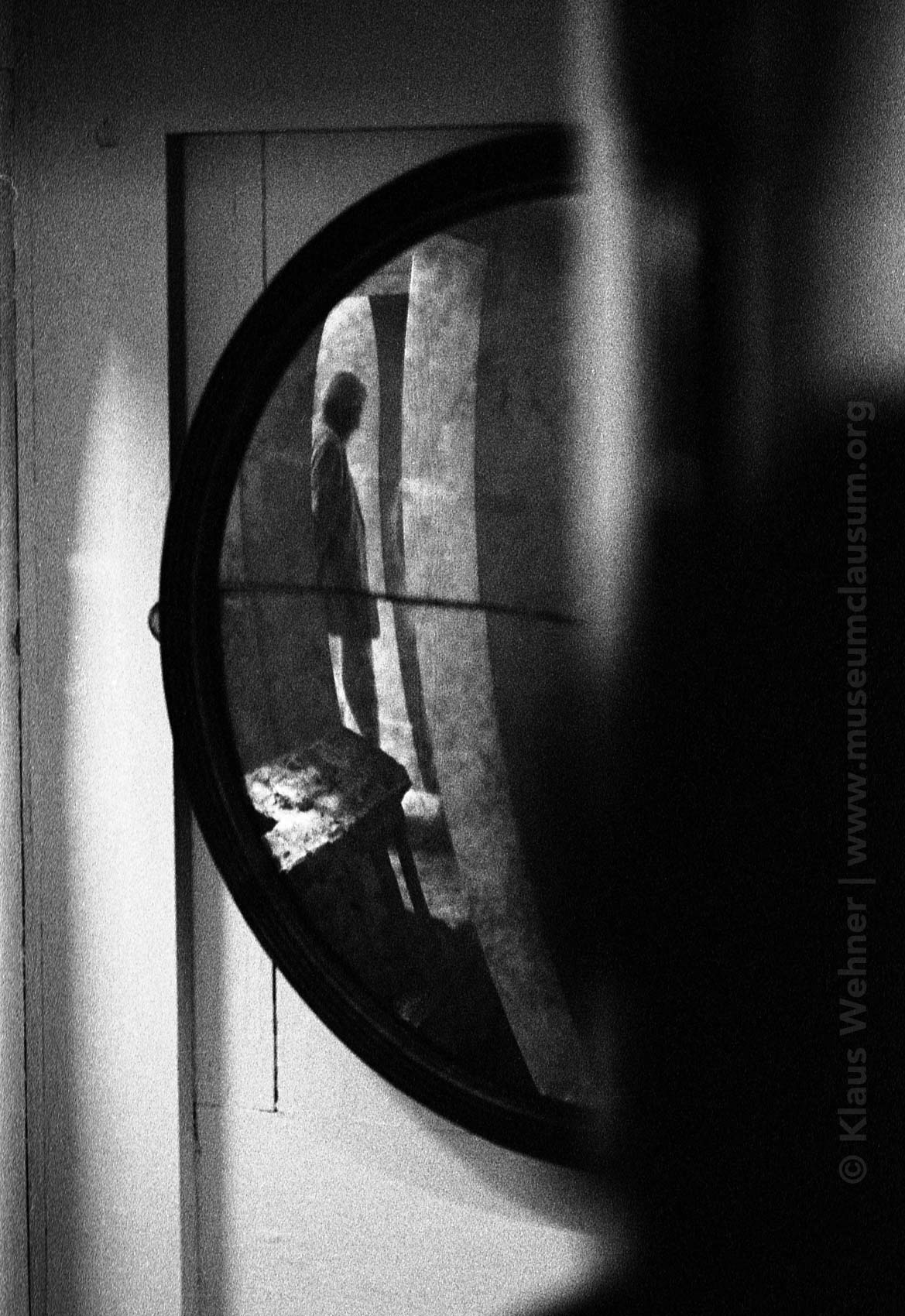 Sir John Soane's Museum: Black and white crop into a convex mirror showing a visitor's silhouette in the Crypt..