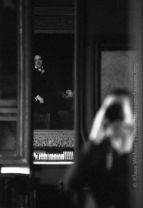 photo of Klaus seen in a mirror with Soane's portrait reflected in the distance